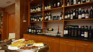 A kitchen with wooden cabinets and a countertop displaying various bottles of wine. - Brindor Hotel (Poirino)