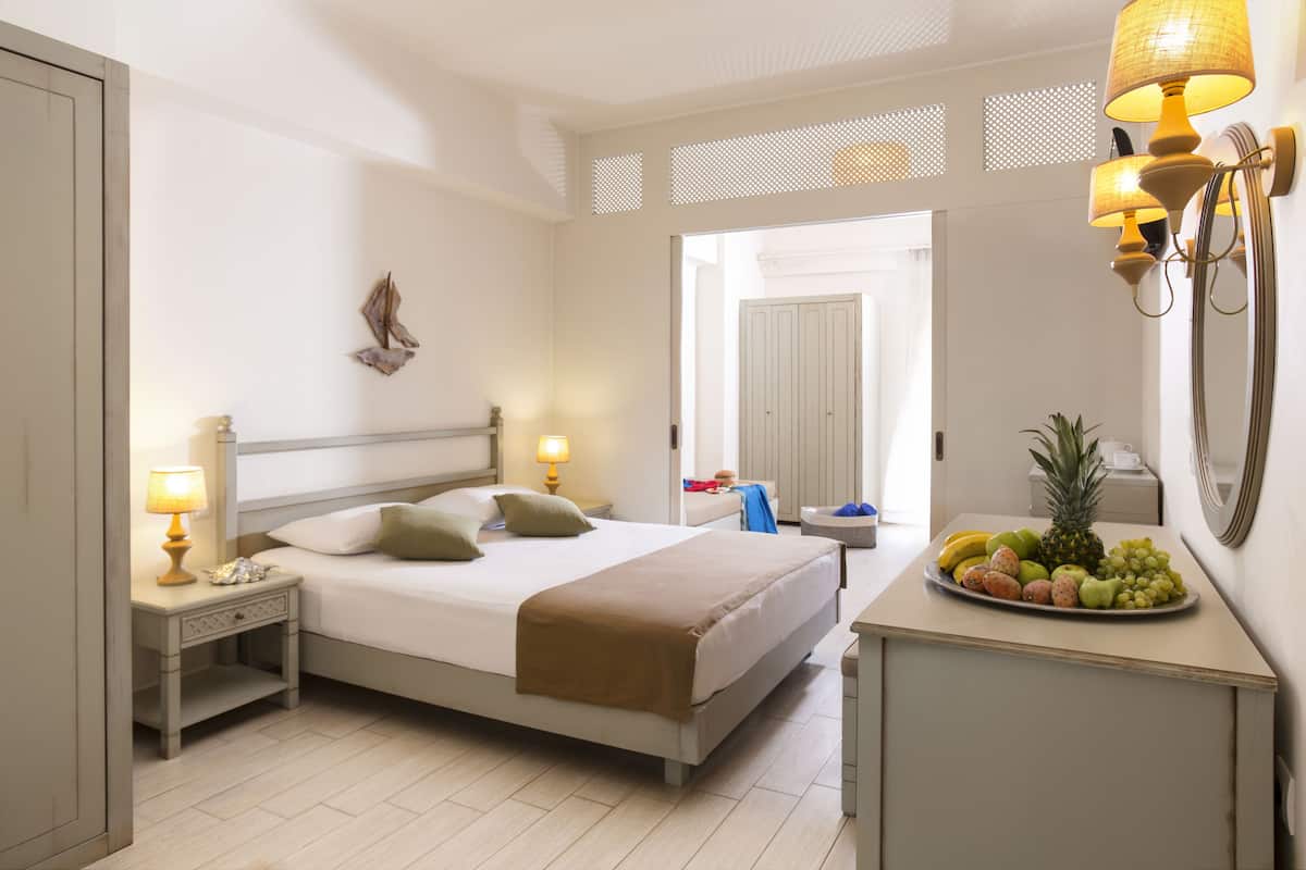 Una habitación de hotel con una cama, lámparas de noche, un frutero y un espejo.
