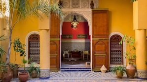 A courtyard with a tiled floor, wooden doors, and a central archway. - Palais Nazha Fes - Luxury Lodging (Fes)