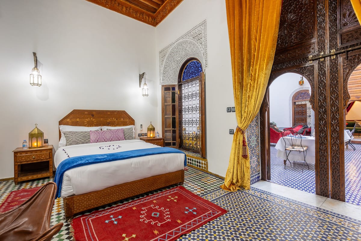 A bedroom with a bed, nightstands, and a view of a dining area.