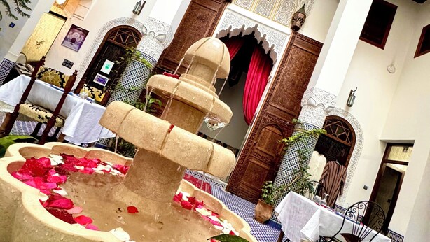A courtyard with a fountain, tables, chairs, and traditional decor. - Palais Nazha Fes - Luxury Lodging (Fes)