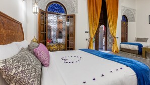 A room with a bed, a sofa, and a window with intricate patterns. - Palais Nazha Fes - Luxury Lodging (Fes)