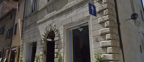 Edificio histórico con fachada de piedra, entrada central con arco y un cartel que indica que no se permite el estacionamiento.