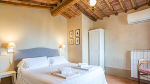 A hotel room with a bed, bedside lamps, a wardrobe, and a radiator. - Palazzo Mosela Alla Porta (Montepulciano)