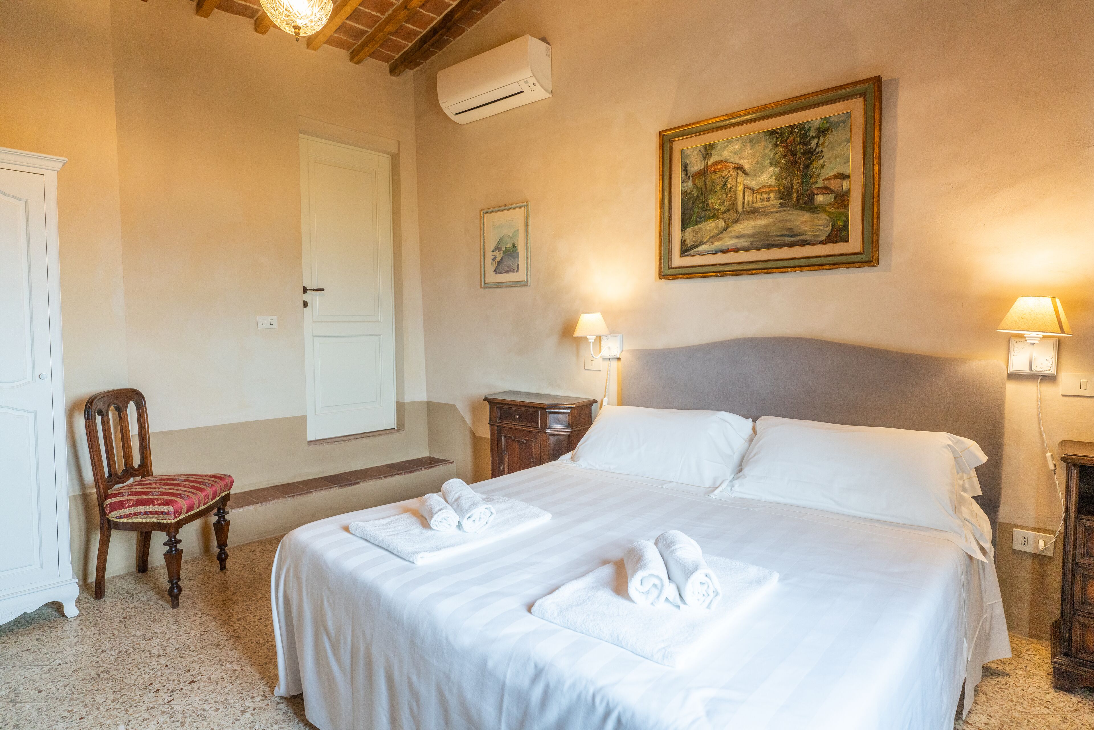 Une chambre d’hôtel avec un grand lit, une chaise, une table de chevet et un tableau au mur.