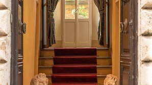 A grand entrance with a red carpet leading to a staircase, flanked by two lion statues. - Palazzo Mosela Alla Porta (Montepulciano)