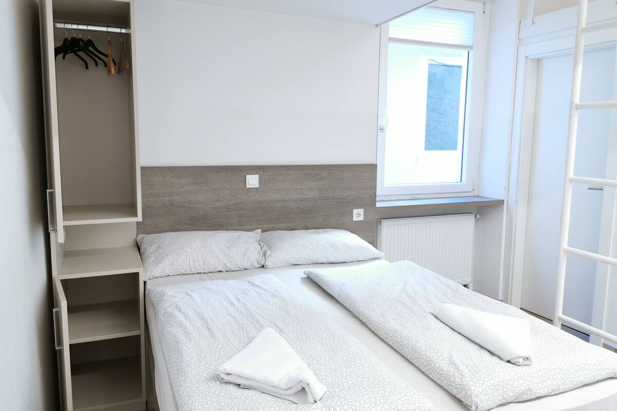 A bedroom with a bed, a wardrobe, a window, and a radiator.