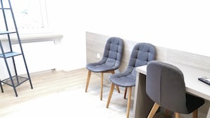 A modern office space with two grey upholstered chairs, a white desk, and a black metal ladder.