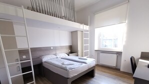 A modern bedroom with a bunk bed, a desk, and a window with a view.