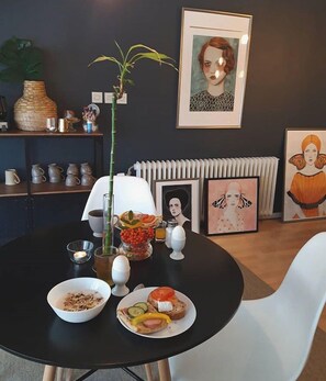 A dining table with breakfast items, a vase with a plant, and framed artwork on the wall. - Morris Hotel (Örebro)