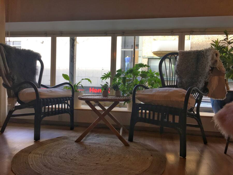 Una habitación con dos sillas de mimbre, una mesita redonda y una alfombra tejida.