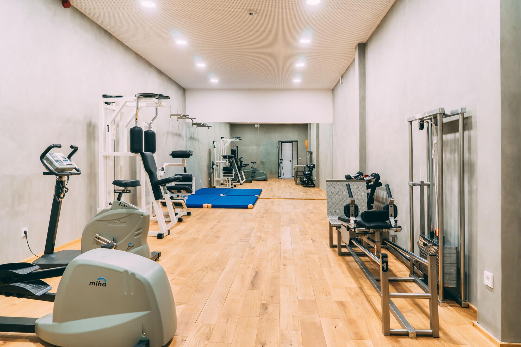 Un gimnasio con equipo de cardio, máquinas de pesas y una colchoneta azul.