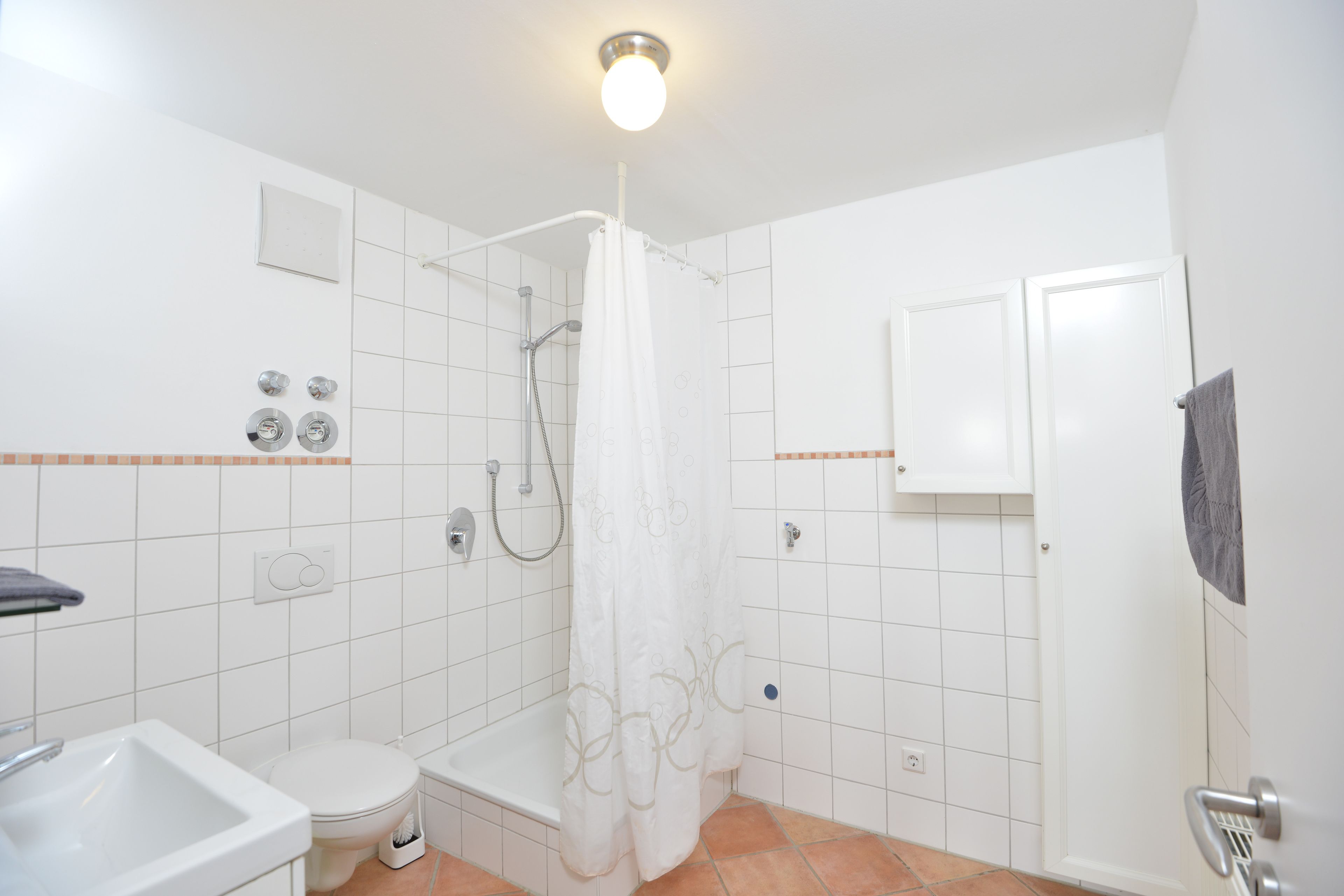 Un baño con ducha, inodoro, lavamanos y un armario.