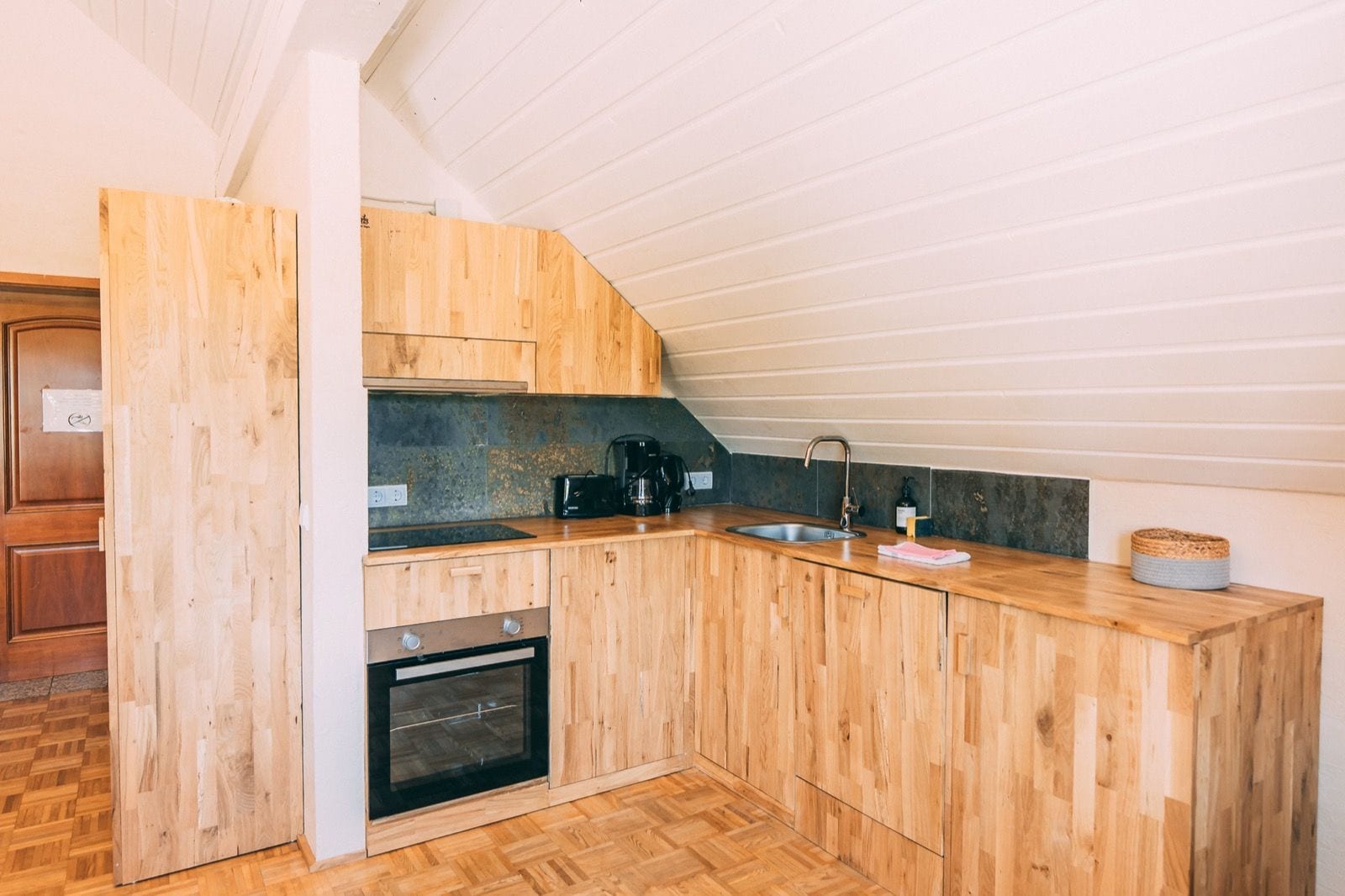 A compact kitchen with wooden cabinetry, a built-in oven, and a sink.