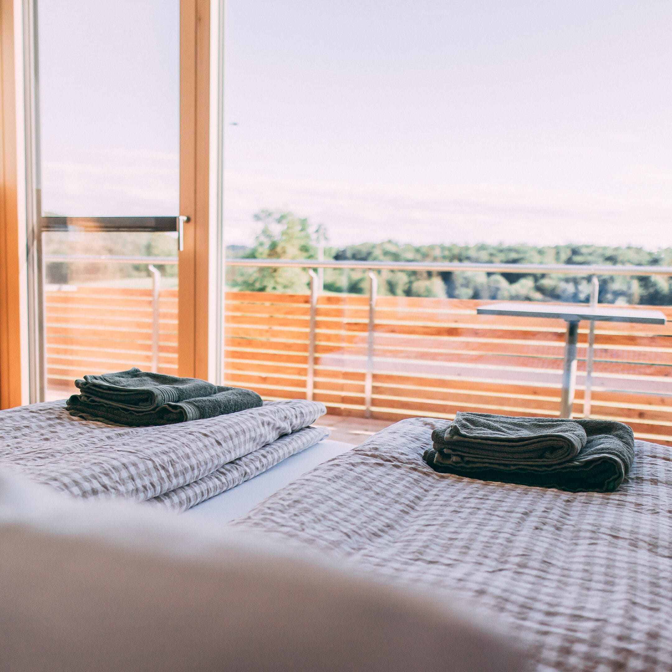 A hotel room with a balcony, a bed with a textured bedspread, and a view of the outdoors.