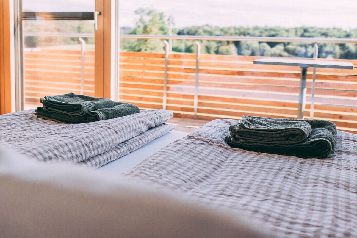 Habitación de hotel con balcón, cama con cubrecama texturizado y vistas al exterior.
