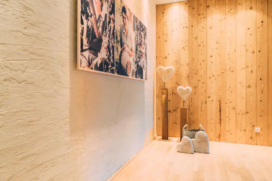 A room with a wooden wall and a large abstract painting. There are two heart-shaped decorations on the floor.