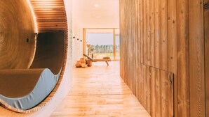 Ein modernes Interieur mit einer gewölbten Holzwand, Holzboden und einer Sitzecke mit einer Bank und Kissen.