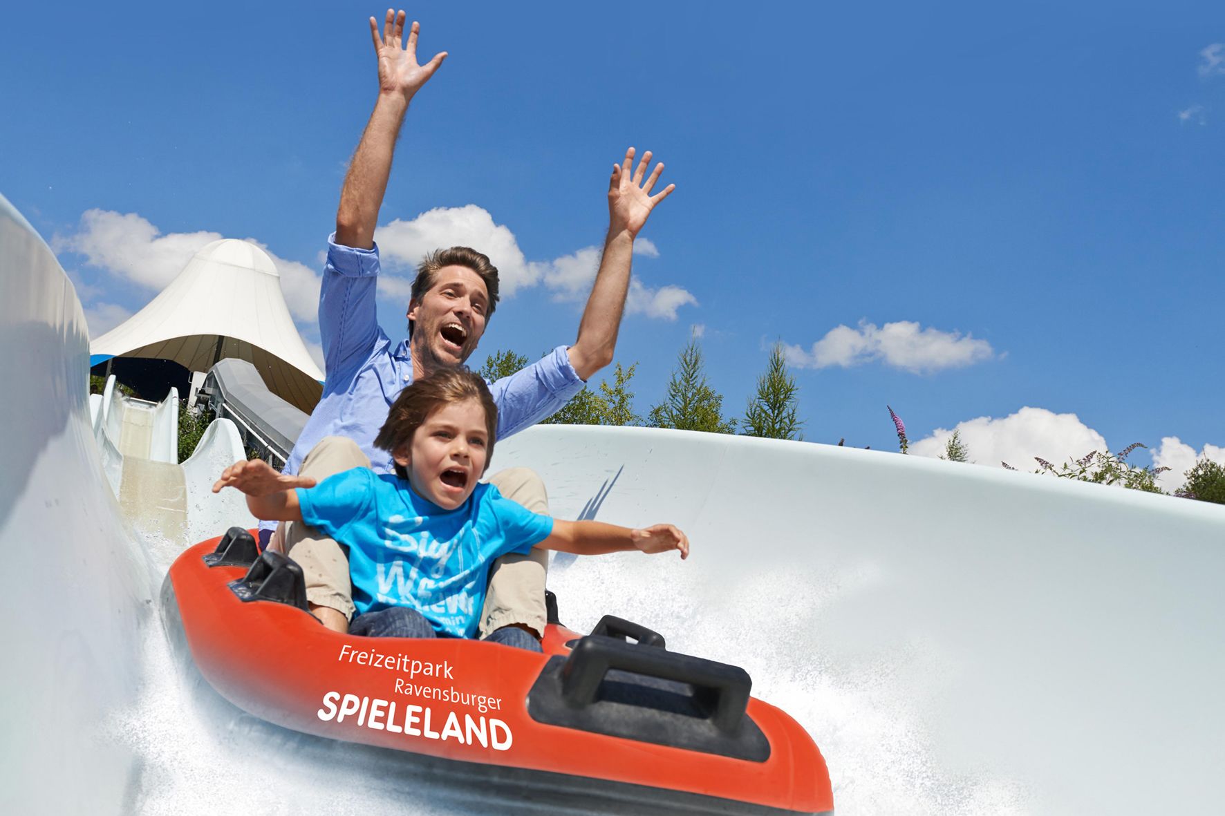 A water slide at a theme park with a clear sky and trees in the background.