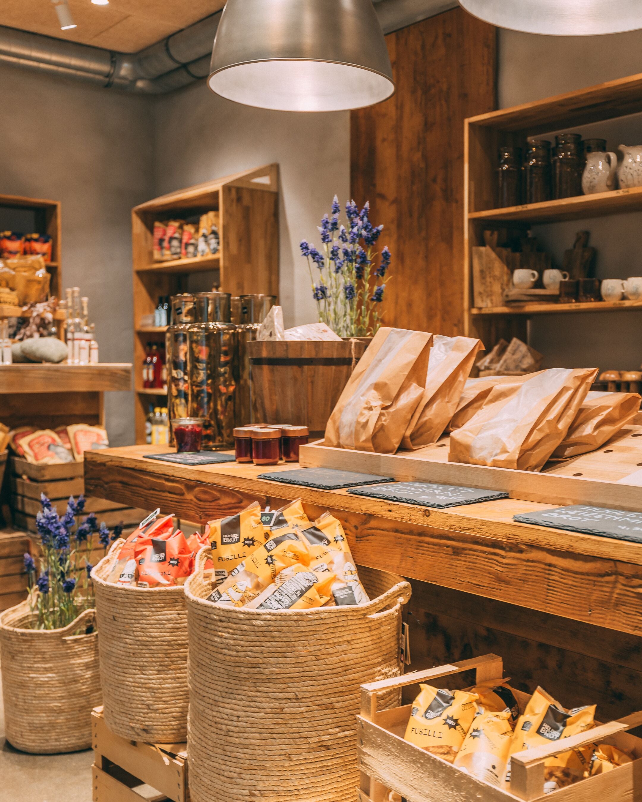 Un mostrador de panadería con panes y pasteles, cestas de madera y una lámpara colgante.