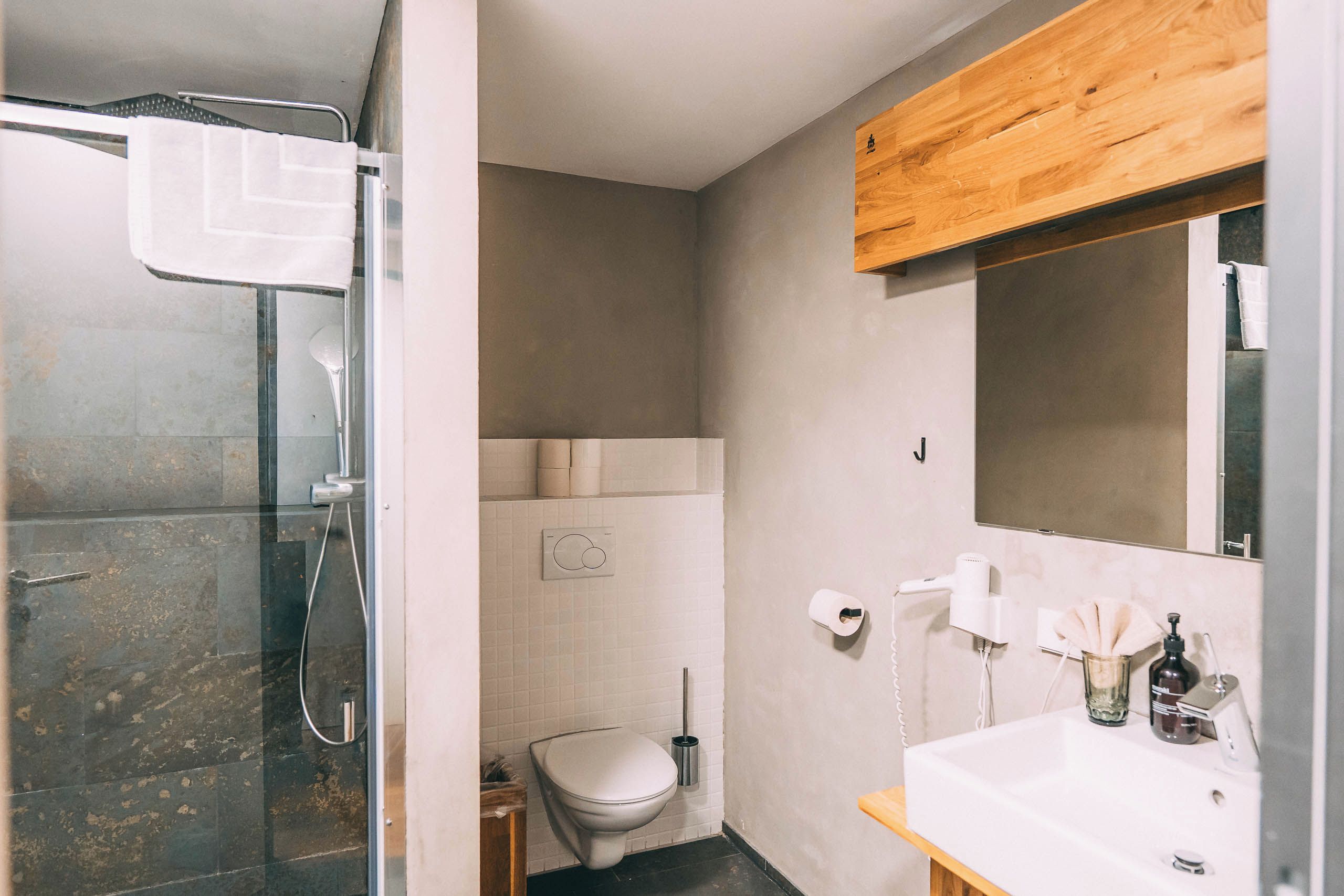Baño con ducha, inodoro, lavabo y espejo.