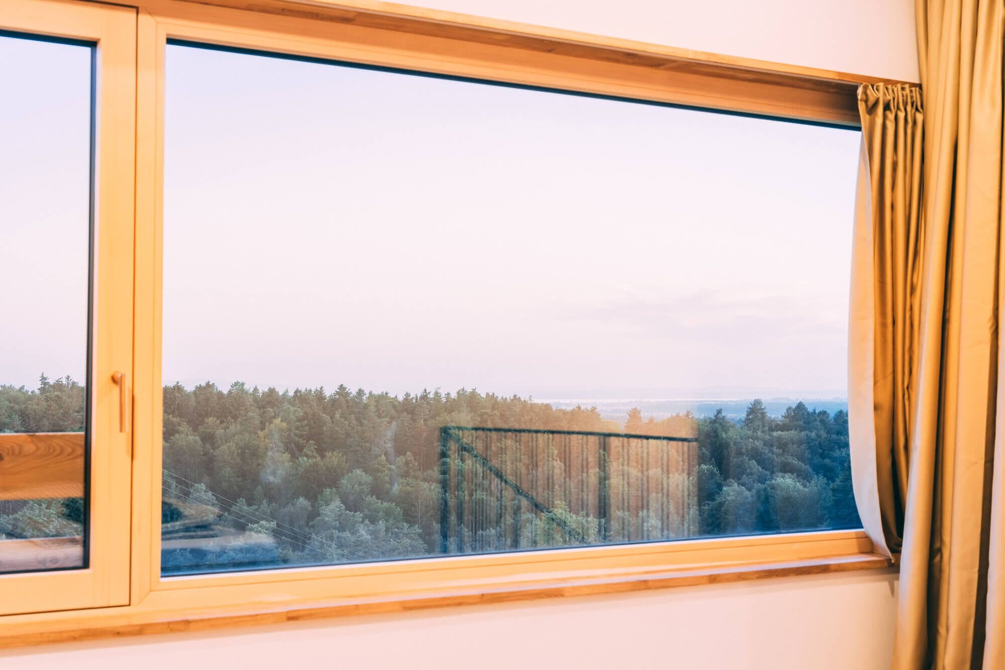 A room with a large window overlooking a forested area.