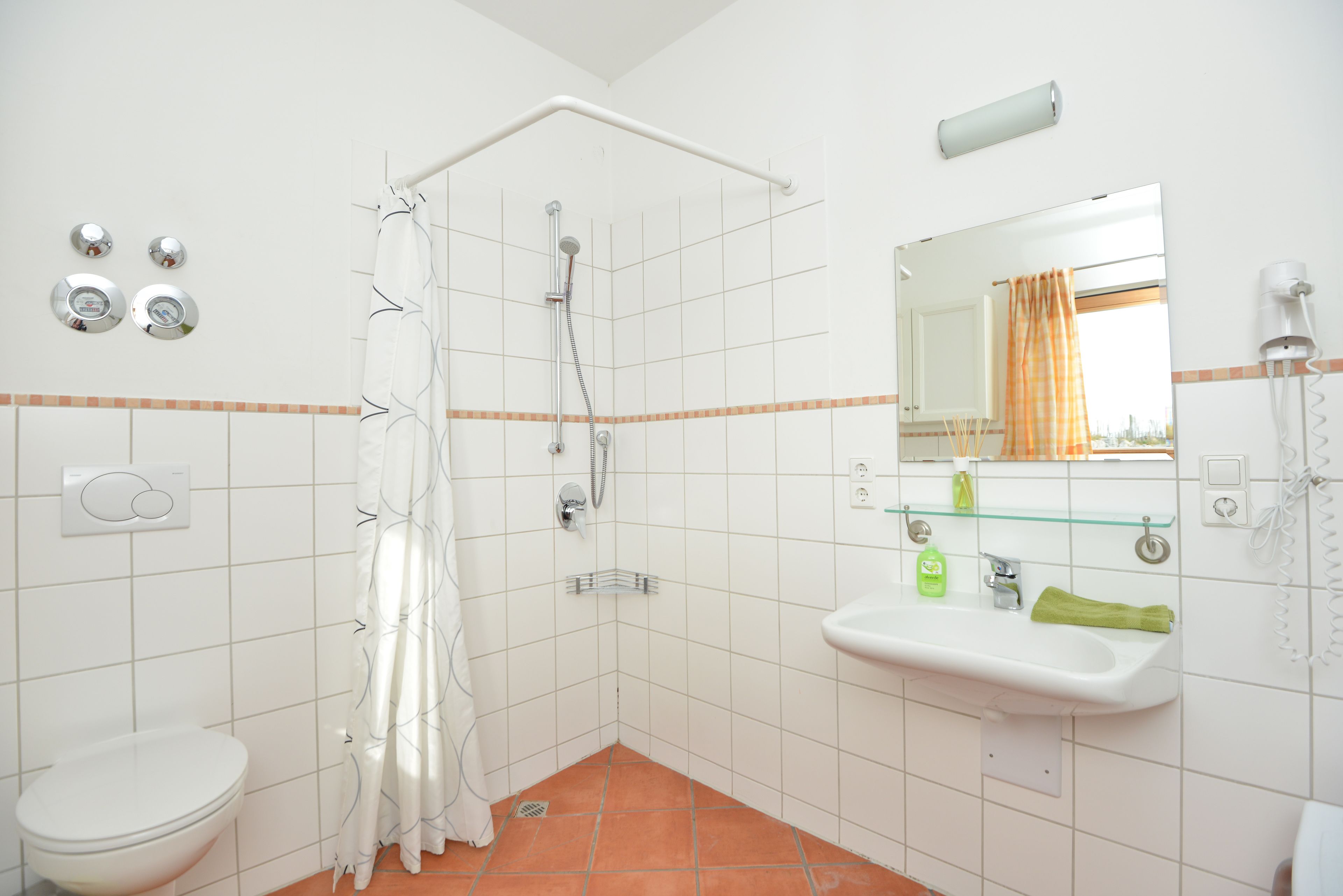 A bathroom with a shower, toilet, sink, and mirror.