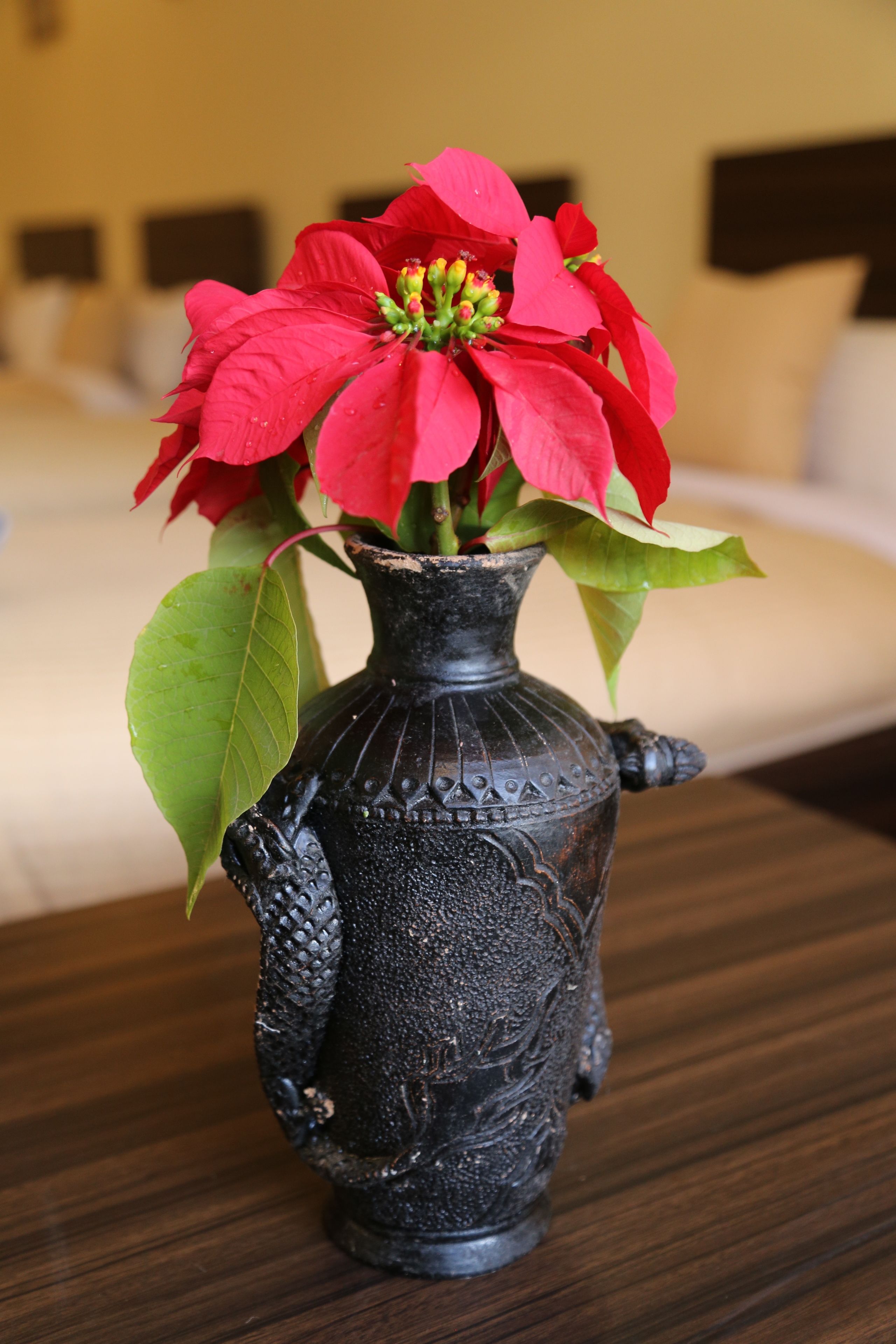 A black vase with a floral arrangement on a wooden table.