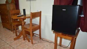A small room with a wooden table, a wooden chair, a black Galanz refrigerator, and a wooden dresser. - Sugar Patch Inn (Hopkins)