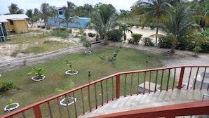A balcony with a red railing overlooking a grassy area with small trees and a sandy path. - Sugar Patch Inn (Hopkins)