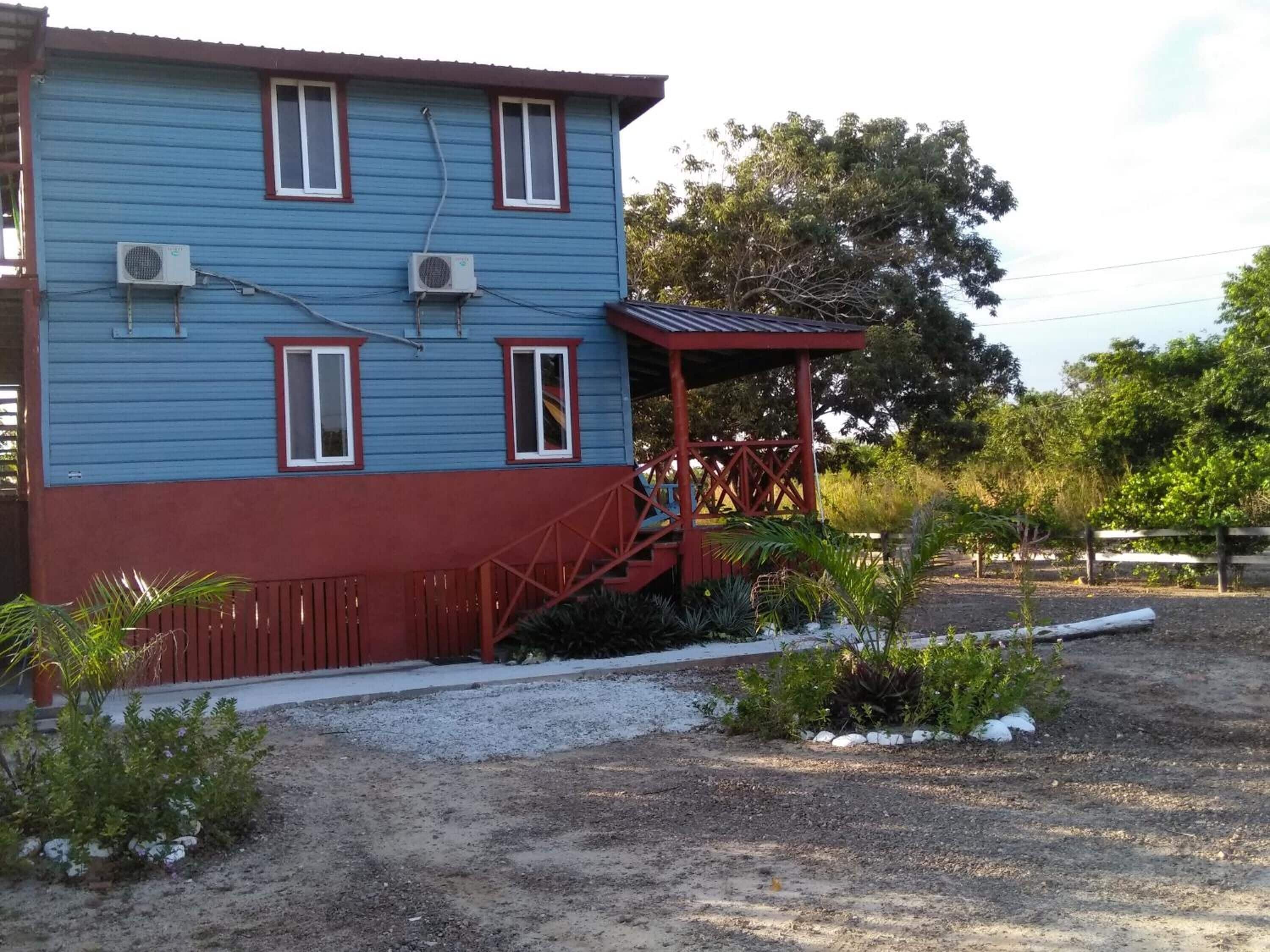 A two-story building with a red and blue exterior, a covered porch, and air conditioning units.