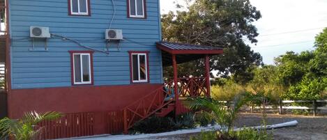 A two-story building with a red and blue exterior, a covered porch, and air conditioning units.