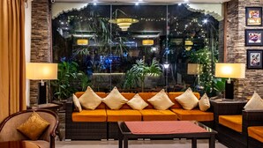 Una sala moderna con un conjunto de sofá, dos mesitas de noche con lámparas, una mesa de centro y un amplio ventanal con luces decorativas.