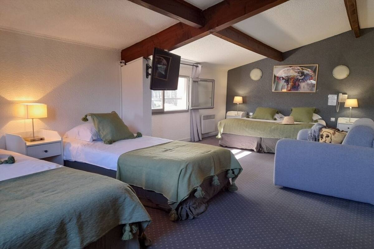 A hotel room with two beds, a sofa, a TV, and a painting on the wall.