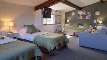 A hotel room with two beds, a sofa, a TV, and a painting on the wall.
