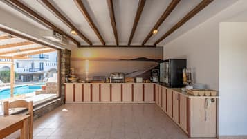 A kitchen with a view of a pool and sunset, wooden cabinets, and a phone on the counter.