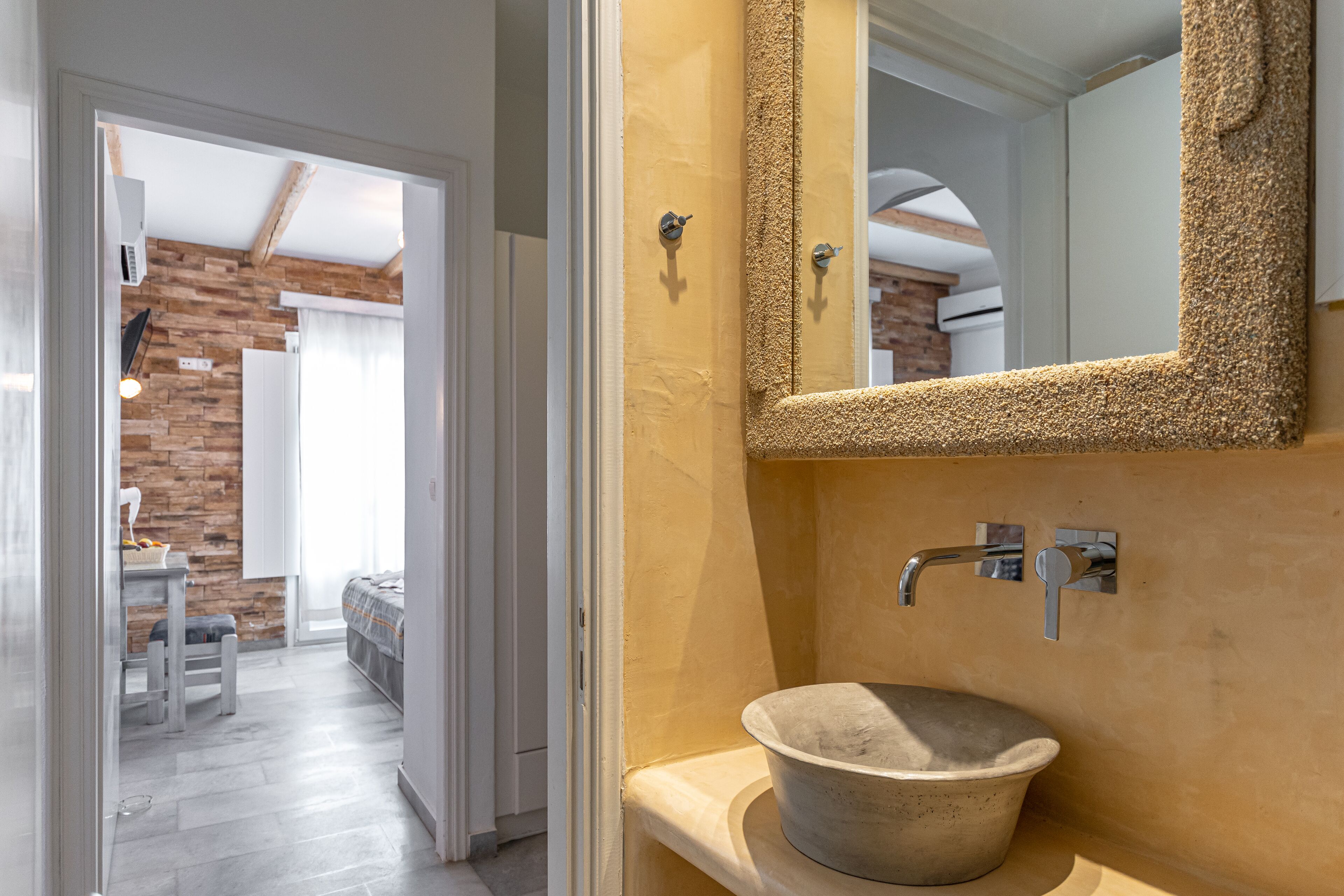 A bathroom with a stone sink, a mirror with a textured frame, and a wooden wall.