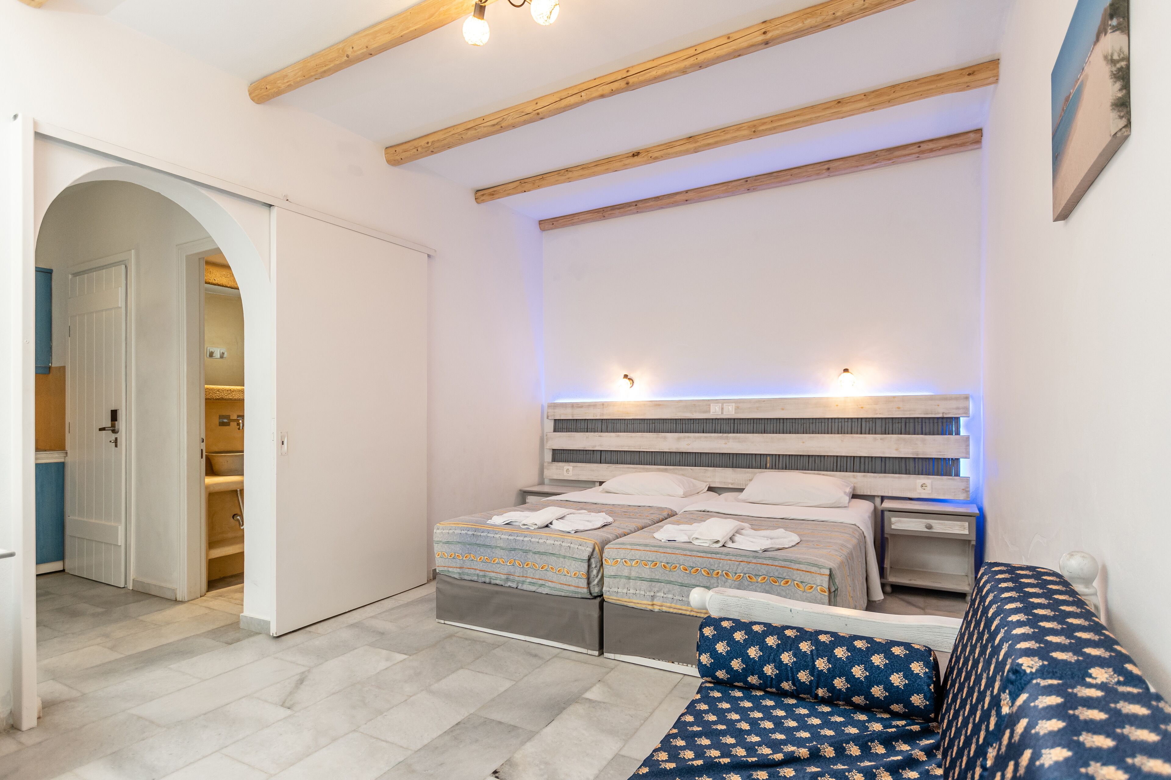 Un dormitorio con dos camas, techo de madera, armario empotrado y una mesita de noche pequeña.