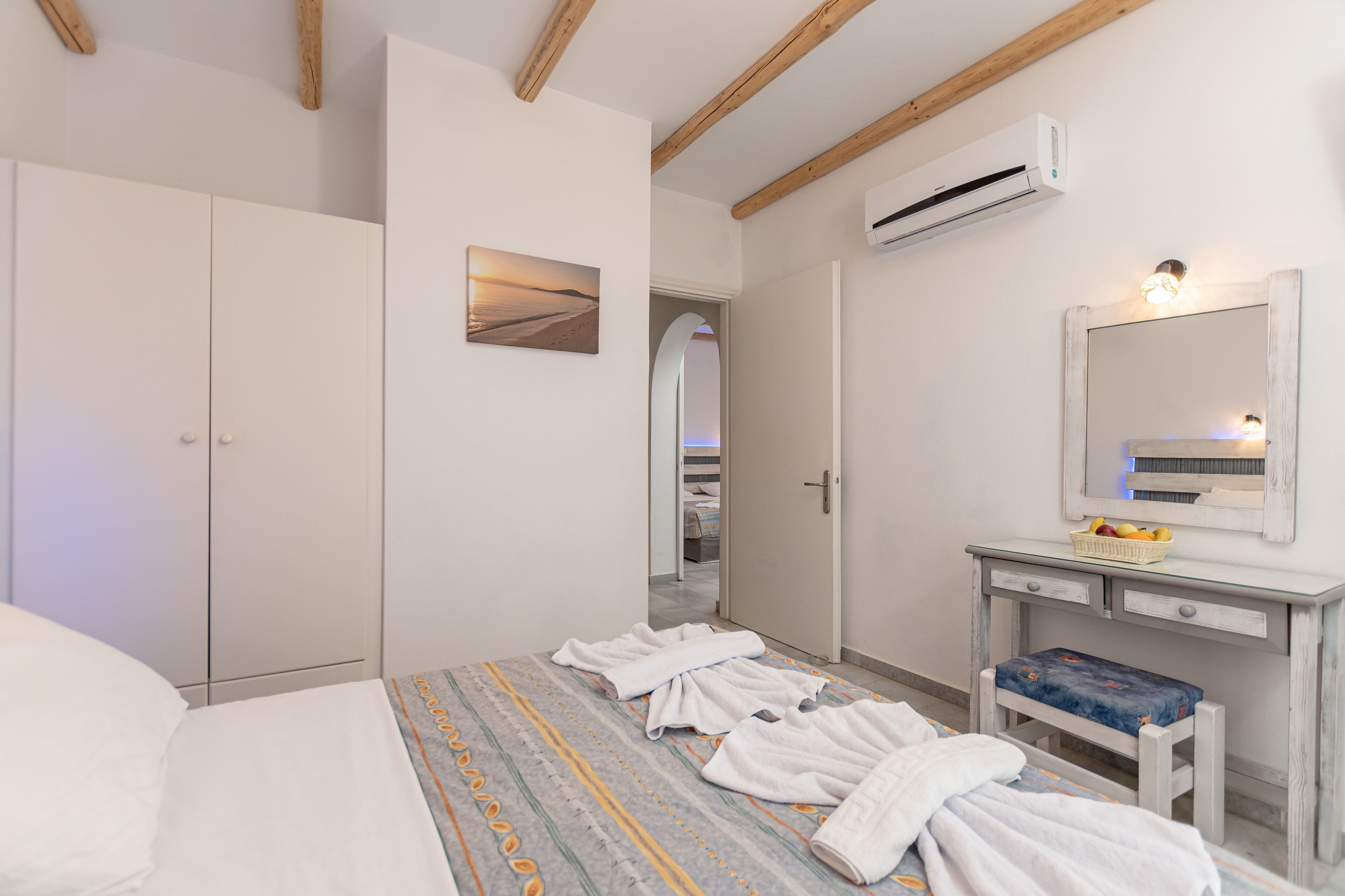 Une chambre d’hôtel comprenant un lit, une table de chevet avec un miroir, un banc et une armoire.