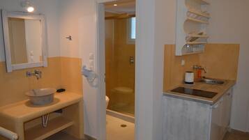 Ein Badezimmer mit Waschbecken, Spiegel, Toilette und Duschbereich.