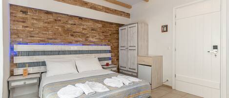 A bedroom with a brick-patterned headboard, a bed with white linens, a nightstand, a wardrobe, and a door.