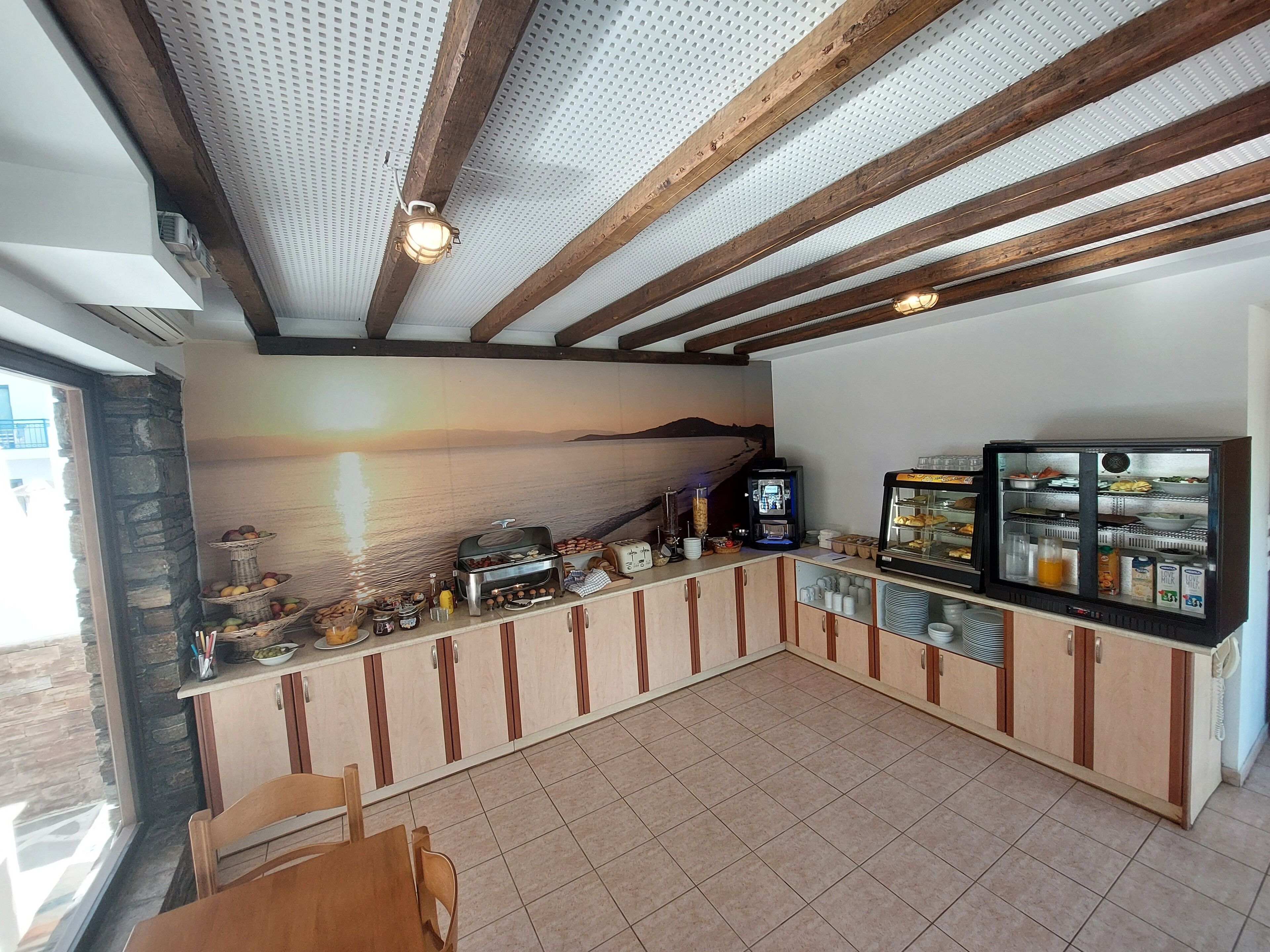 Una barra de desayuno con pared de piedra, vigas de madera y un mural de un atardecer.