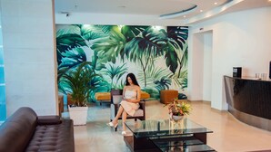A modern lobby with a large tropical mural, a reception desk, a sofa, and a coffee table. - Hotel Plaza Las Americas Cali (Cali)