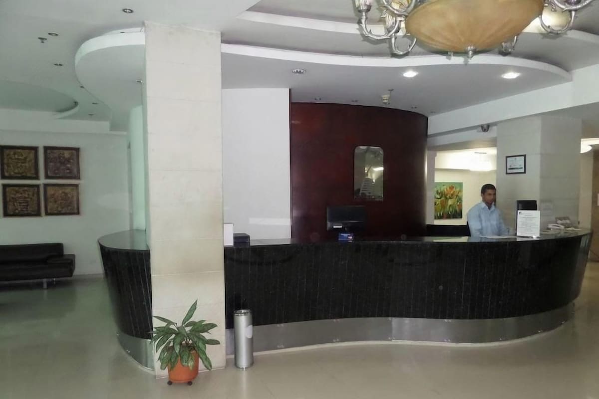A reception area with a curved reception desk, a potted plant, and a man standing behind the desk.
