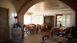 A dining area with multiple tables, chairs, and a wooden barrel as a decorative element. - Agriturismo Bacche di Bosco (Verona)