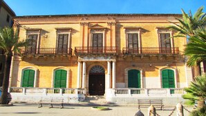 A historic building with a central entrance, symmetrical windows, and a balcony. - Casa Vacanza Ondablu (Ispica)