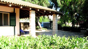 A building with a tiled roof, stone pillars, and a covered patio area. - Casa Vacanza Ondablu (Ispica)