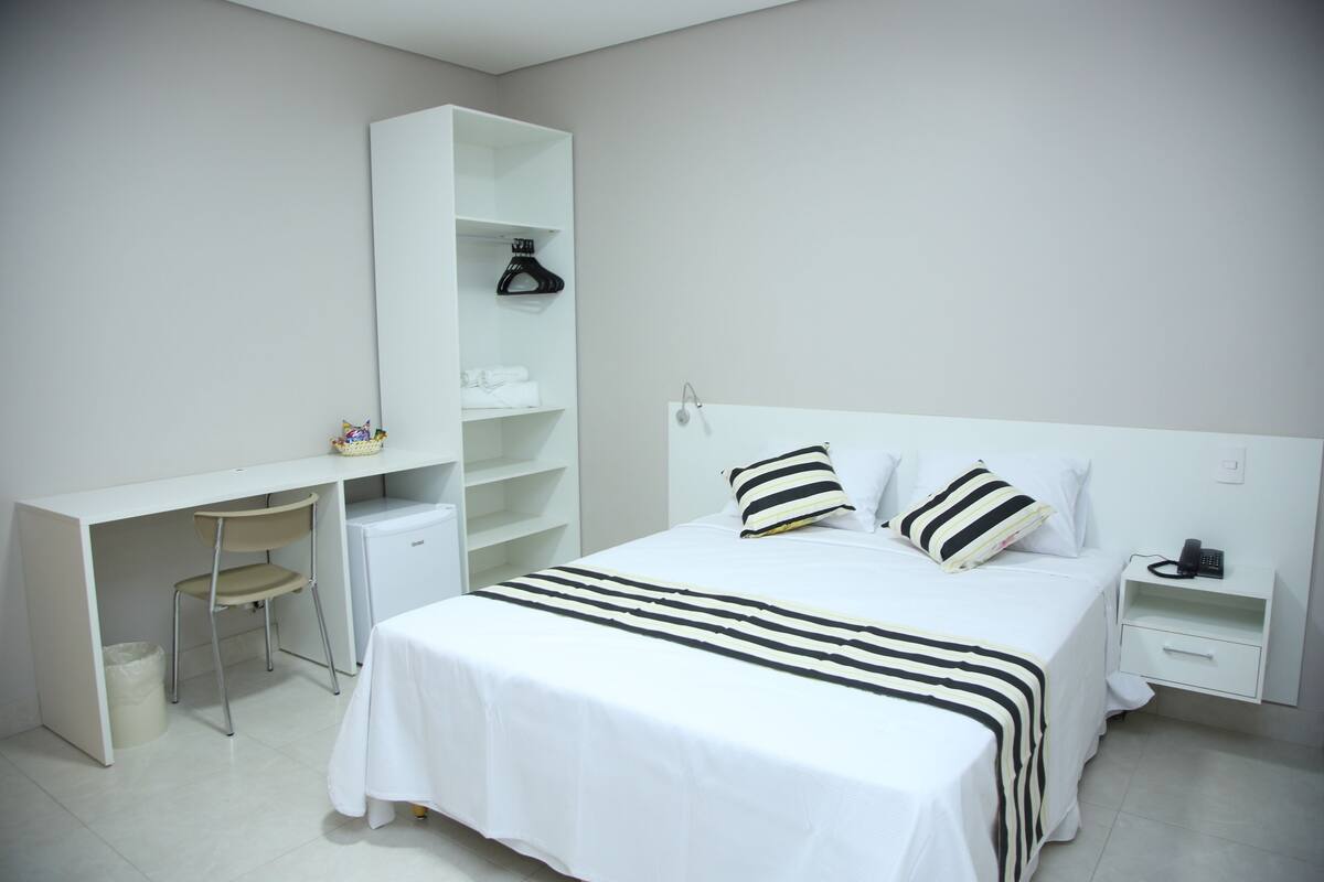 Ein Schlafzimmer mit einem Bett, einem Schreibtisch, einem Stuhl und einem Kleiderschrank.