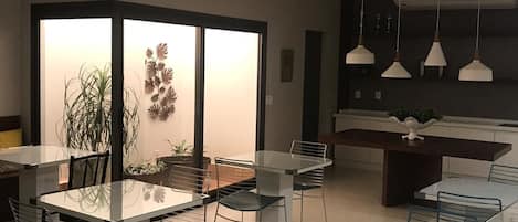 Un comedor moderno con un separador de vidrio, una mesa central y sillas.