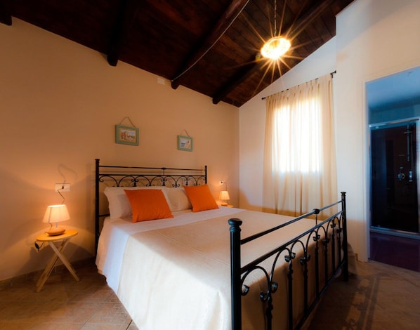 A bedroom with a bed, a nightstand, a window with curtains, and a ceiling light.